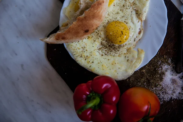 Fechar a placa com ovos fritos e tomates perto de garfo e faca — Fotografia de Stock