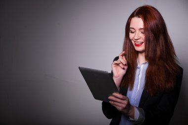 saçlı gülümseyen kız tablet gri arka plan üzerinde kullanma