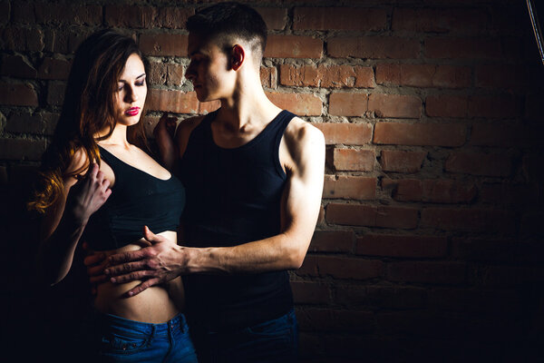 Attractive couple standing with bike on brick wall background