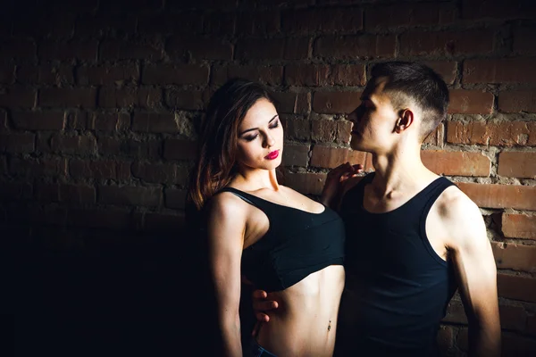 Atractiva pareja de pie con bicicleta en el fondo de la pared de ladrillo — Foto de Stock