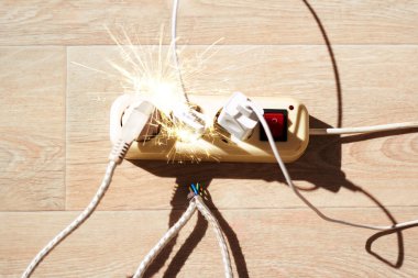 Fotoğraf, yerde yatan uzatma kablosunu geniş bir akım tüketimiyle gösteriyor. Büyük enerji tüketimi kavramı, tehlikeli yangın