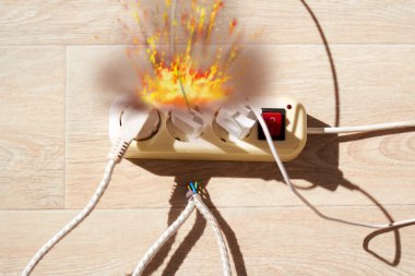 Fotoğraf, yerde yatan uzatma kablosunu geniş bir akım tüketimiyle gösteriyor. Büyük enerji tüketimi kavramı, tehlikeli yangın