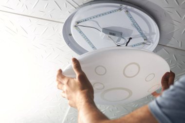 Bir elektrik teknisyeni düşük tüketimli LED lambayı konut elektrik sistemine dönüştürür, kapağı kapatır