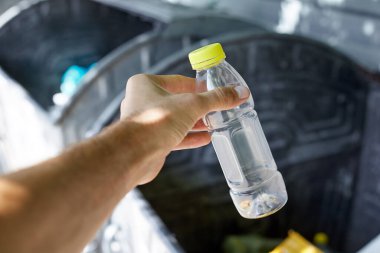 Temizlikle ilgilenen plastik bir şişeyi çöpe at..