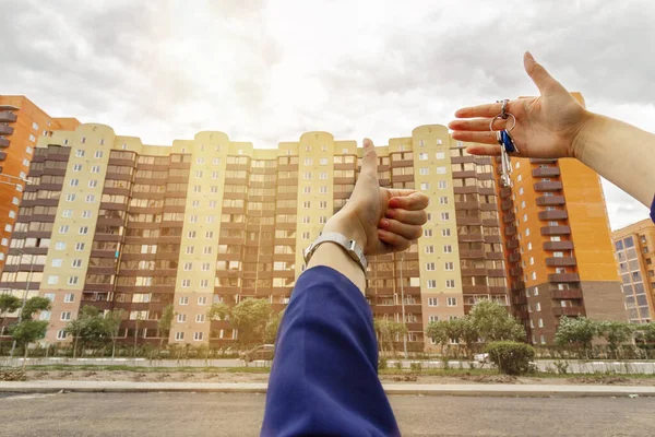 Hand with house keys the second hand shows the class, the concept of buying a home.