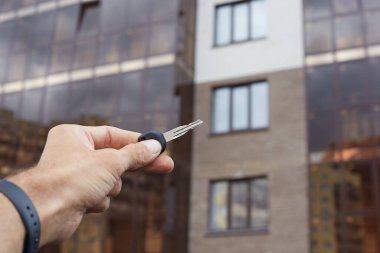 Binanın arka planında evin anahtarlarını taşıyan bir adam..