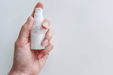 Elinde beyaz bir sıvı, kozmetik ve higen konsepti ile tüpü tutuyor.