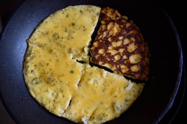 Sarı omlete özenli bir şekilde odaklan, siyah tavadaki çöreklere odaklan.