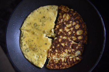 Sarı omlete özenli bir şekilde odaklan, siyah tavadaki çöreklere odaklan.