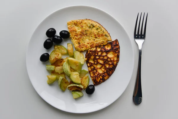Kahvaltıda beyaz tabakta üst manzara. Yağda yumurta, kabak, siyah zeytin..