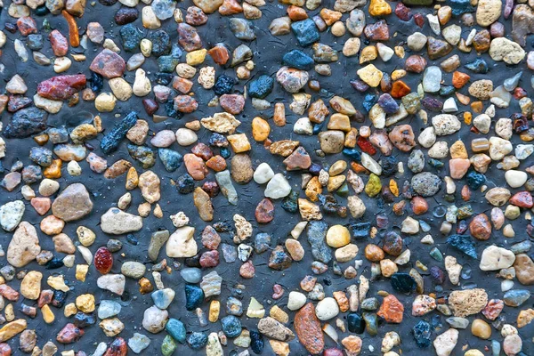 多彩的小石块压在灰色的地面上 背景是由不同岩石的小而明亮的多色块体构成的 碎石材质感细腻 顶部视野均匀 — 图库照片