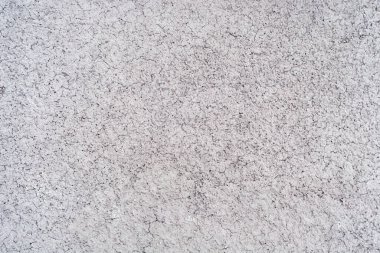 Küçük çatlakları olan beton gri duvar. Yumuşak ışıklandırmada kabartmalı gri arka plan. Gri doku soyutlamasında küçük çatlaklar
