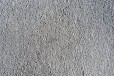 Gri, kabataslak bir duvar. Kaba boyanmış yüzeyin gri dokusu