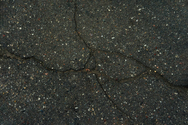 темный фон старые асфальтовые трещины, смешанные с мелким разноцветным гравием