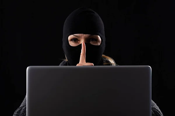 Ηλεκτρονικός τρομοκράτης με μάσκα σε μαύρο φόντο πίσω από λάπτοπ. — Φωτογραφία Αρχείου
