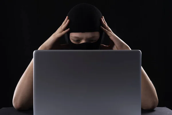 Ηλεκτρονικός τρομοκράτης με μάσκα σε μαύρο φόντο πίσω από λάπτοπ. — Φωτογραφία Αρχείου