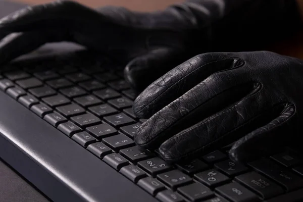 Cybercriminal hands in gloves on laptop keyboard — Stock Photo, Image