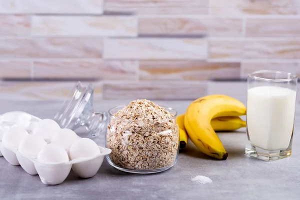 Oat pancakes with banana. Step by step cooking process. Ingredients top view. Bananas, milk, eggs, oats, salt. Wooden table background. Copy space. — Stock Image Oat Pancakes Banana Step Step Cooking Process Ingredients Top View Stock Photo