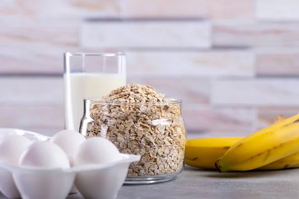 Oat pancakes with banana. Step by step cooking process. Ingredients top view. Bananas, milk, eggs, oats, salt. Wooden table background. Copy space. — Stock Image Oat Pancakes Banana Step Step Cooking Process Ingredients Top View Royalty Free Stock Images