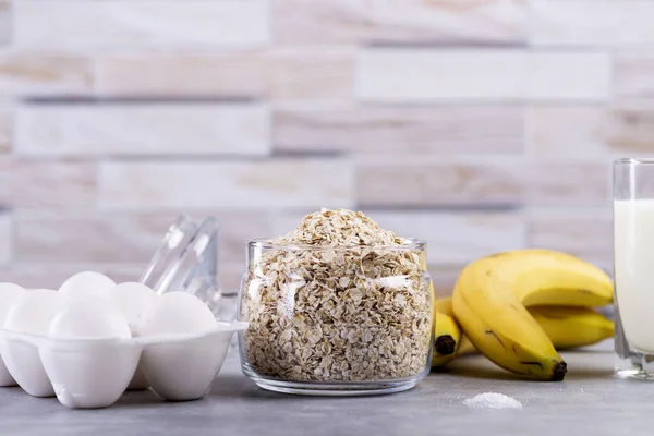 Oat pancakes with banana. Step by step cooking process. Ingredients top view. Bananas, milk, eggs, oats, salt. Wooden table background. Copy space. — Stock Image Oat Pancakes Banana Step Step Cooking Process Ingredients Top View Stock Picture