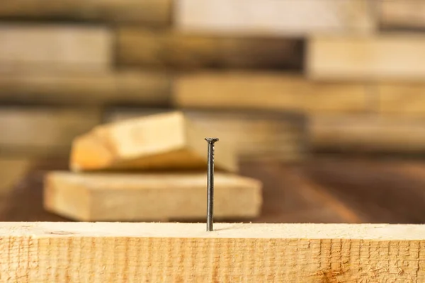 Close-up of a single nail stuck in a wooden board.