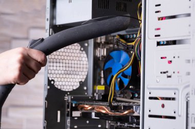 Bir masaüstü bilgisayarının sistem birimini elektrikli süpürgeyle tozdan temizlemek