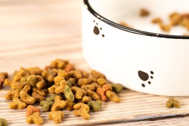 Ahşap bir arka planda bir kasede evcil hayvan yiyeceği. Ahşap bir arka planda kediler ya da köpekler için kuru yiyecek.