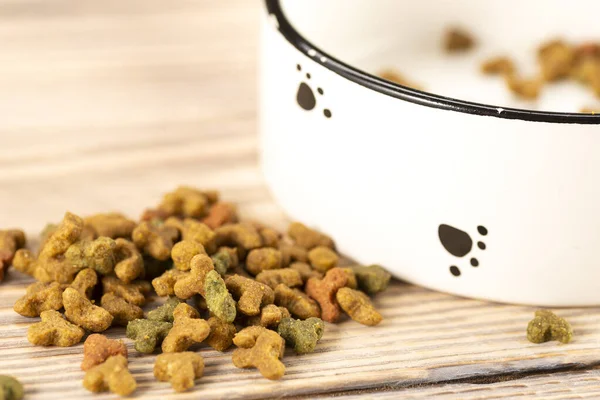 Pet food in a bowl on a wooden vintage background. Dry food for dogs or cats in a bowl on a wooden background