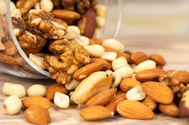 Farklı fındık karışımı cam bir kavanozdan masaya dökülür. Doku ve arka plan olarak fındık, makro.