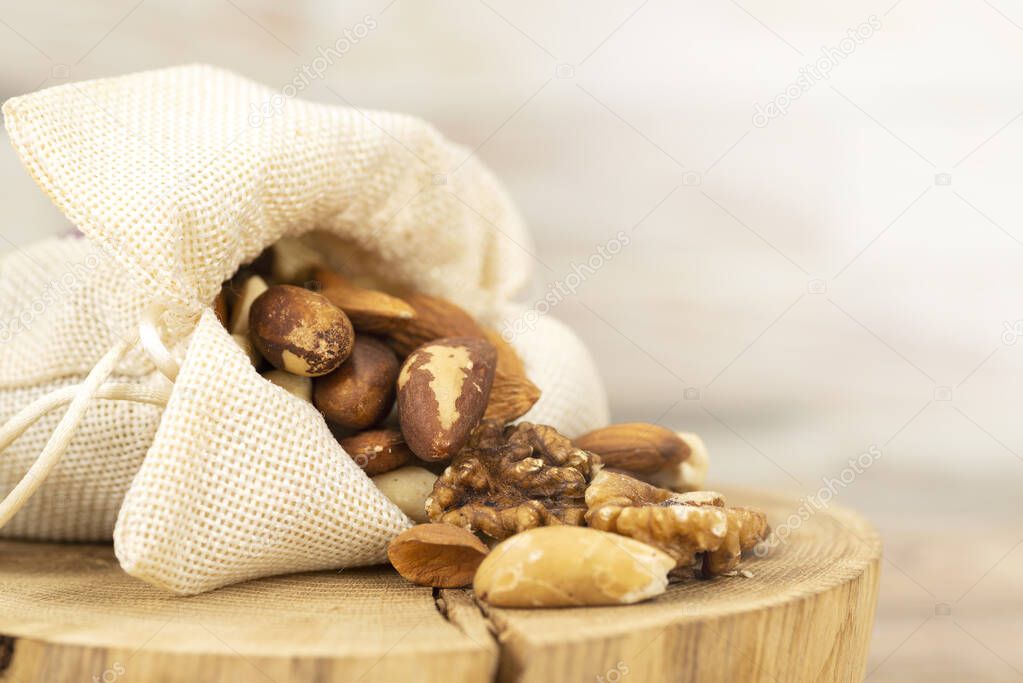 the mixture of nuts is poured out of the bag onto a wooden stand. Close-up, macro.
