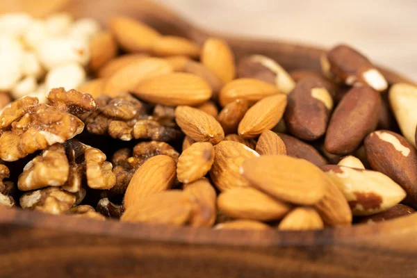 mixture of nuts in a wooden plate close-up.