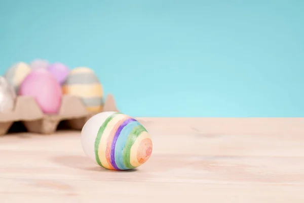 Oeufs de Pâques colorés sur un stand sur une table sur un fond bleu — Photo