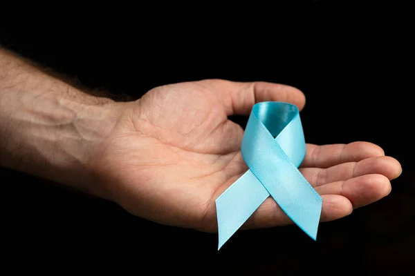 男性的手在深色背景上握着一条蓝色的带子 十一月的健康检查 预防前列腺炎 癌症意识 一个月不刮胡子 — 图库照片