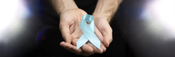 男性的手在深色背景上握着一条蓝色的带子 十一月的健康检查 预防前列腺炎 癌症意识 一个月不刮胡子 — 图库照片