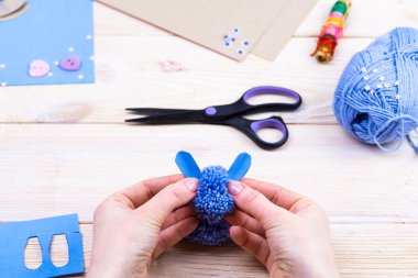 Paskalya dekoru için ponponlardan tavşan yapmayı. Çocuk sanat projesi. Diy konsepti. Eller ponpondan mavi bir Paskalya tavşanı yapar. Adım adım fotoğraf talimatı.