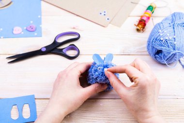 Paskalya dekoru için ponponlardan tavşan yapmayı. Çocuk sanat projesi. Diy konsepti. Eller ponpondan mavi bir Paskalya tavşanı yapar. Adım adım fotoğraf talimatı.