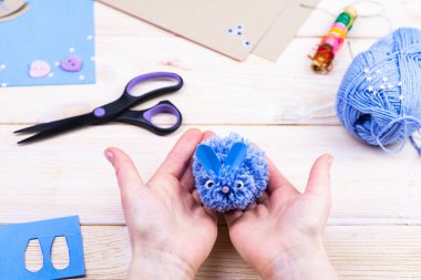 Paskalya dekoru için ponponlardan tavşan yapmayı. Çocuk sanat projesi. Diy konsepti. Eller ponpondan mavi bir Paskalya tavşanı yapar. Adım adım fotoğraf talimatı.