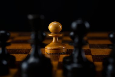 Bir beyaz piyon satranç tahtasındaki siyah taşlardan oluşan bir orduya karşı..