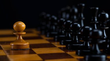 Bir beyaz piyon satranç tahtasındaki siyah taşlardan oluşan bir orduya karşı..