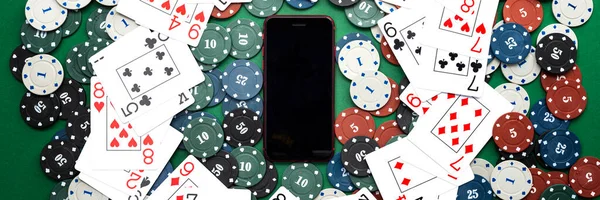 Online casino, mobile casino, mobile phone, chips cards on a green background. Gambling games. View from above.