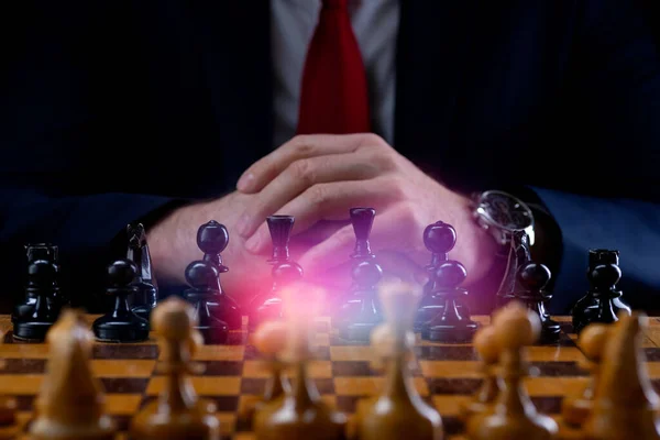 Strategy and business planning concept. A businessman at a chessboard in front of lined up white and black pawns. Strategy and tactics, battle readiness, battle start.