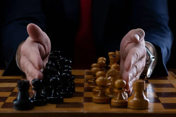 Strategy and business planning concept. A businessman at a chessboard in front of lined up white and black pawns. Strategy and tactics, battle readiness, battle start.