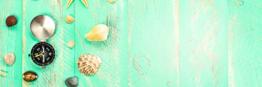 Mavi ahşap masa arkasında deniz kabukları ve pusula. Yaz tatili geçmişi, tatil ve seyahat kavramı.