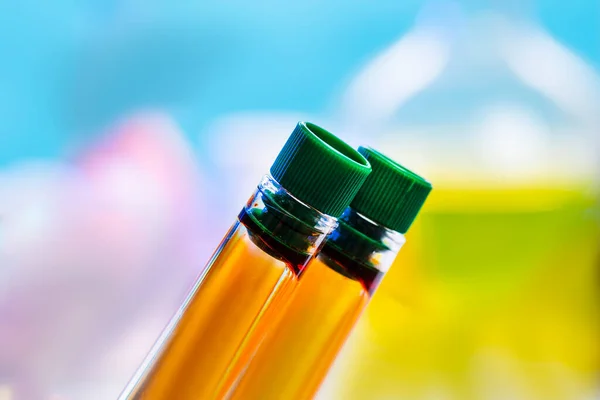 Two chemical test tubes with closed lids with orange liquid on a blue background. Urine test, delivery of urine,