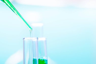 Kimyasal test tüpleri ve yeşil sıvıyla bir kimya laboratuarına yakın olan pipetler..