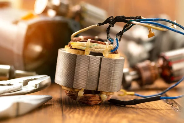 Power tool repair. Details of electrical appliance and repair tools on a wooden table in a repair shop.