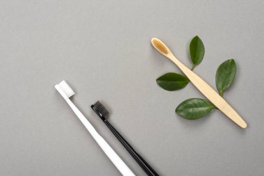 Natural eco friendly bamboo toothbrush and plastic toothbrush on gray background. Choose a plastic or wooden toothbrush. Recycling concept, no waste, no plastic, top view.