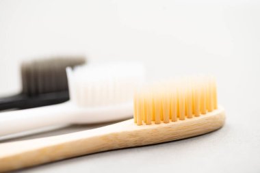 Natural eco-friendly bamboo toothbrush and two plastic toothbrushes on a white background close-up. Choose a plastic or wooden toothbrush. Recycling concept, no waste, no plastic, top view.