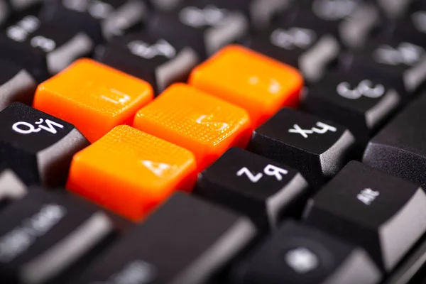 Крупный план оранжевых клавиш со стрелками на черной клавиатуре, вверх, вниз, влево, вправо на клавиатуре игрового компьютера — стоковое фото