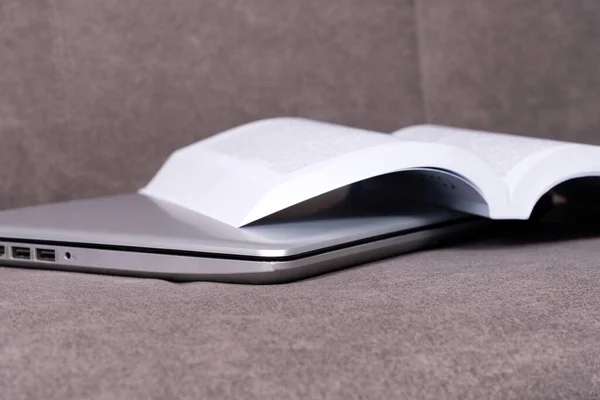 Ноутбук Открытой Книгой Чтения Сером Диване — стоковое фото